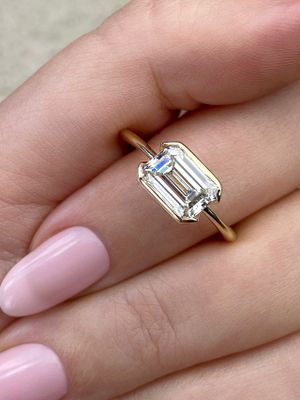 Frank Darling east-west emerald cut half-bezel engagement ring in yellow gold.
