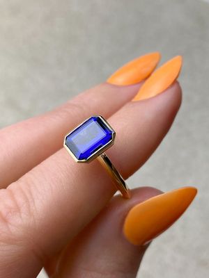 Deep blue emerald cut sapphire bezel set in yellow gold